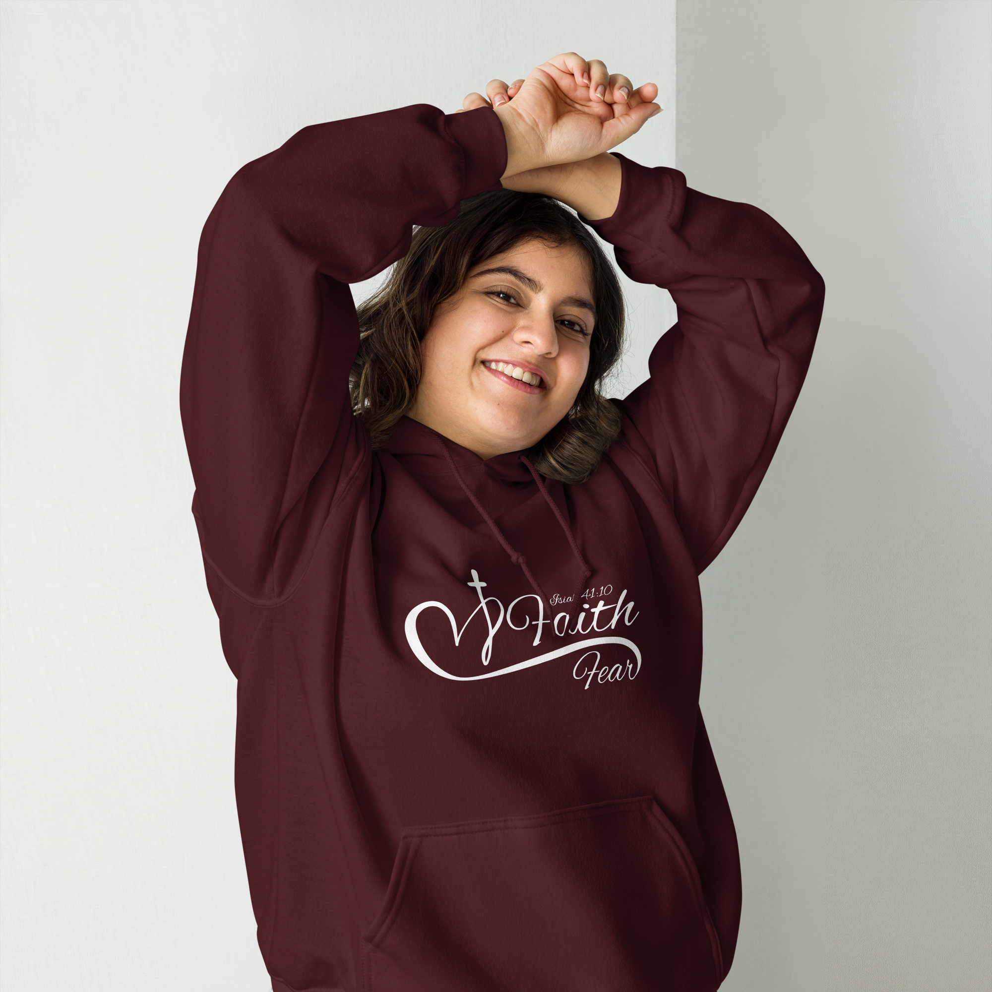 Female model wearing a maroon Christian hoodie with the word “Faith” in larger font above the word “Fear,” separated by a white heart and cross line design, also featuring Isaiah 41:10