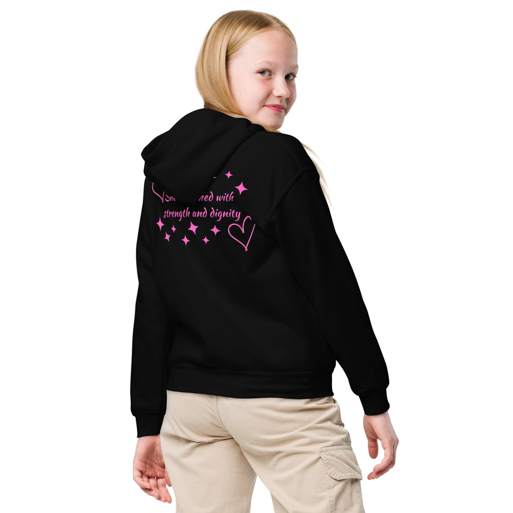 Girl wearing a black girls Christian hoodie showing the back design with dark pink hearts and stars and the Scripture text reading She is clothed with strength and dignity from Proverbs 31:25