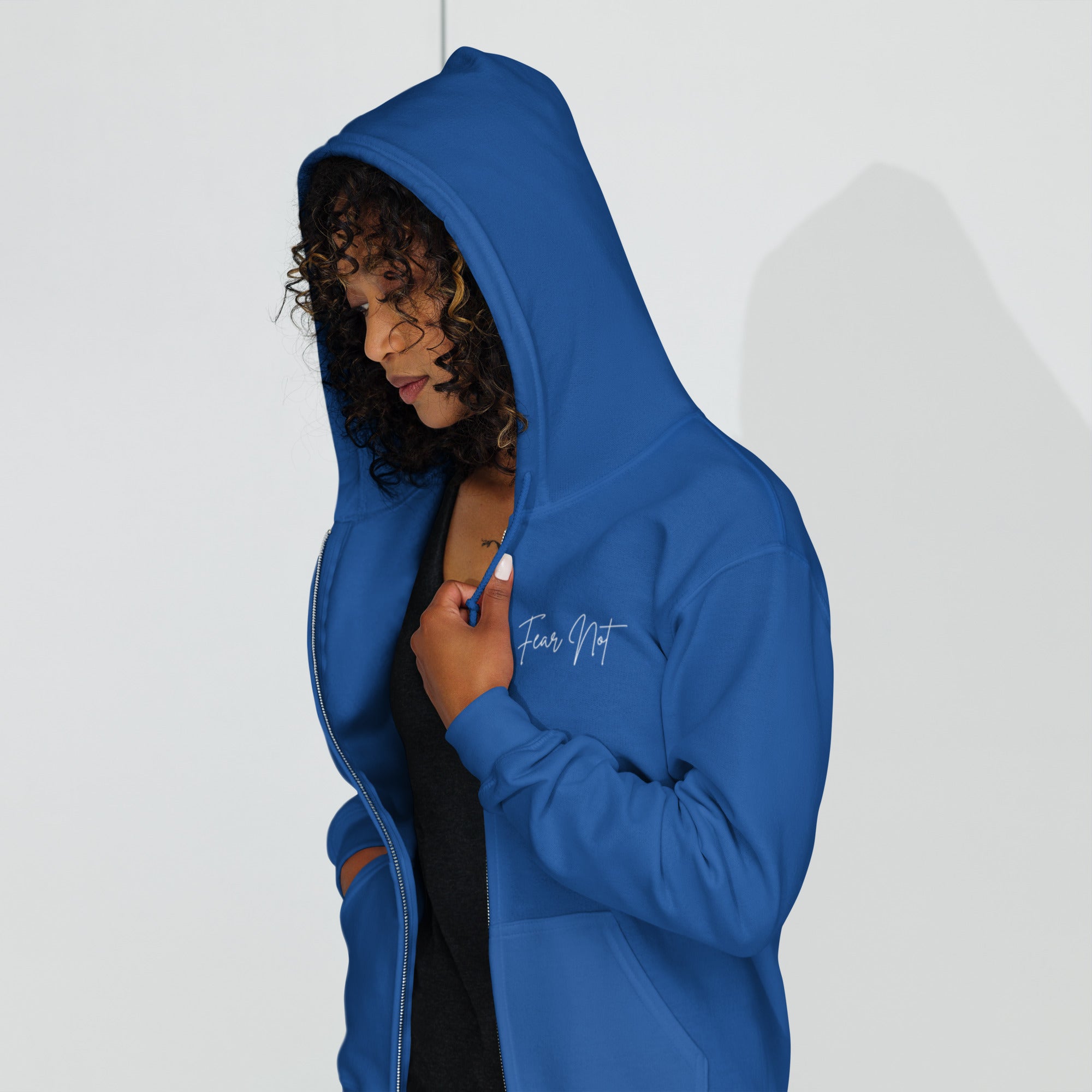 Angled front view of female model wearing the women’s Christian zip hoodie in royal blue turned slightly right showing left chest script text reading Fear Not