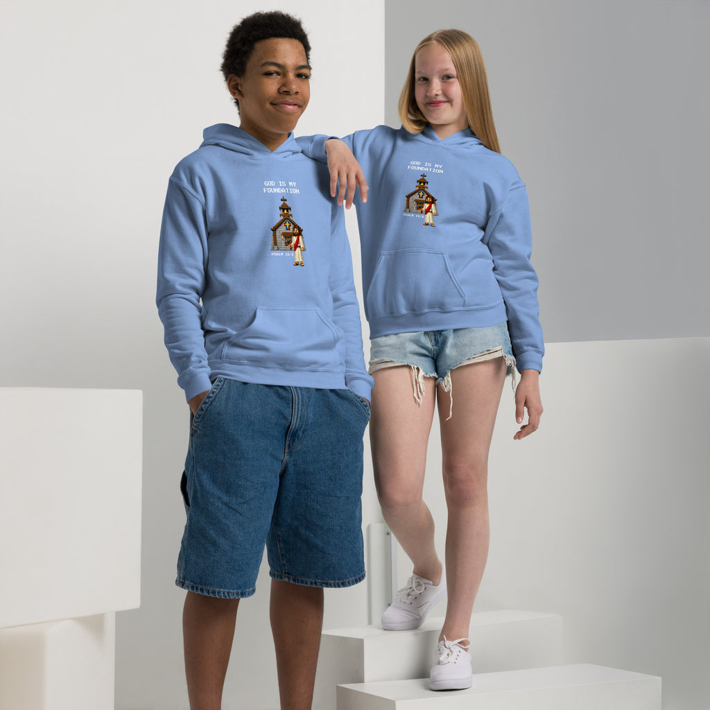Front view of a boy and girl wearing kids’ Christian hoodies in carolina blue, showing a pixel-style church and Jesus illustration with gamer-style text reading “God is my foundation” and “Psalm 18:2”.  