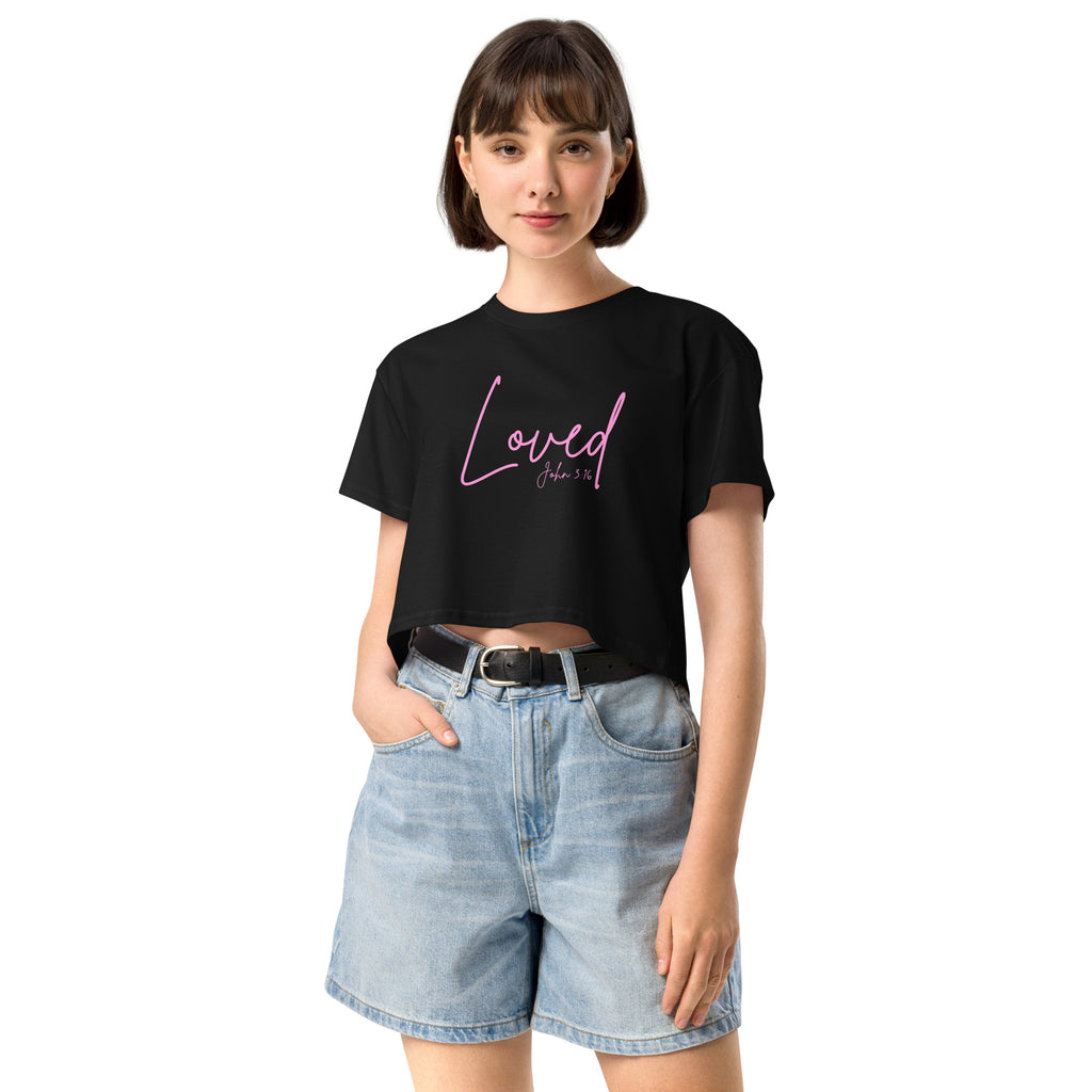 Front view of female model wearing a women’s cropped Christian top in black displaying the word Loved in pink script font with John 3:16 beneath it
