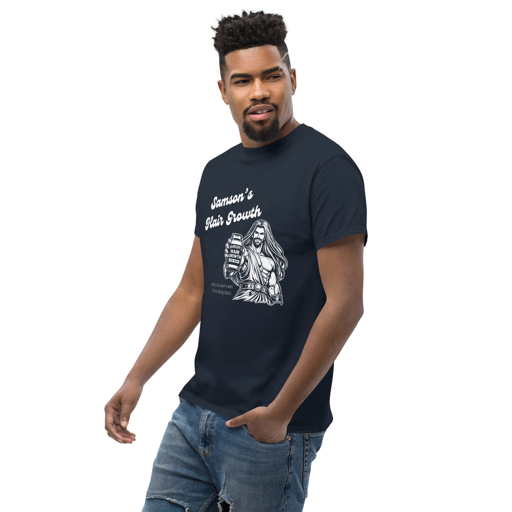 Male model turned slightly to the left wearing a navy men’s Christian humor t-shirt showing the full front design of Samson holding a bottle labeled “Samson’s Hair Growth for Men” with the text “Samson’s Hair Growth” and fine print that reads “Results may vary. Faith Required.”