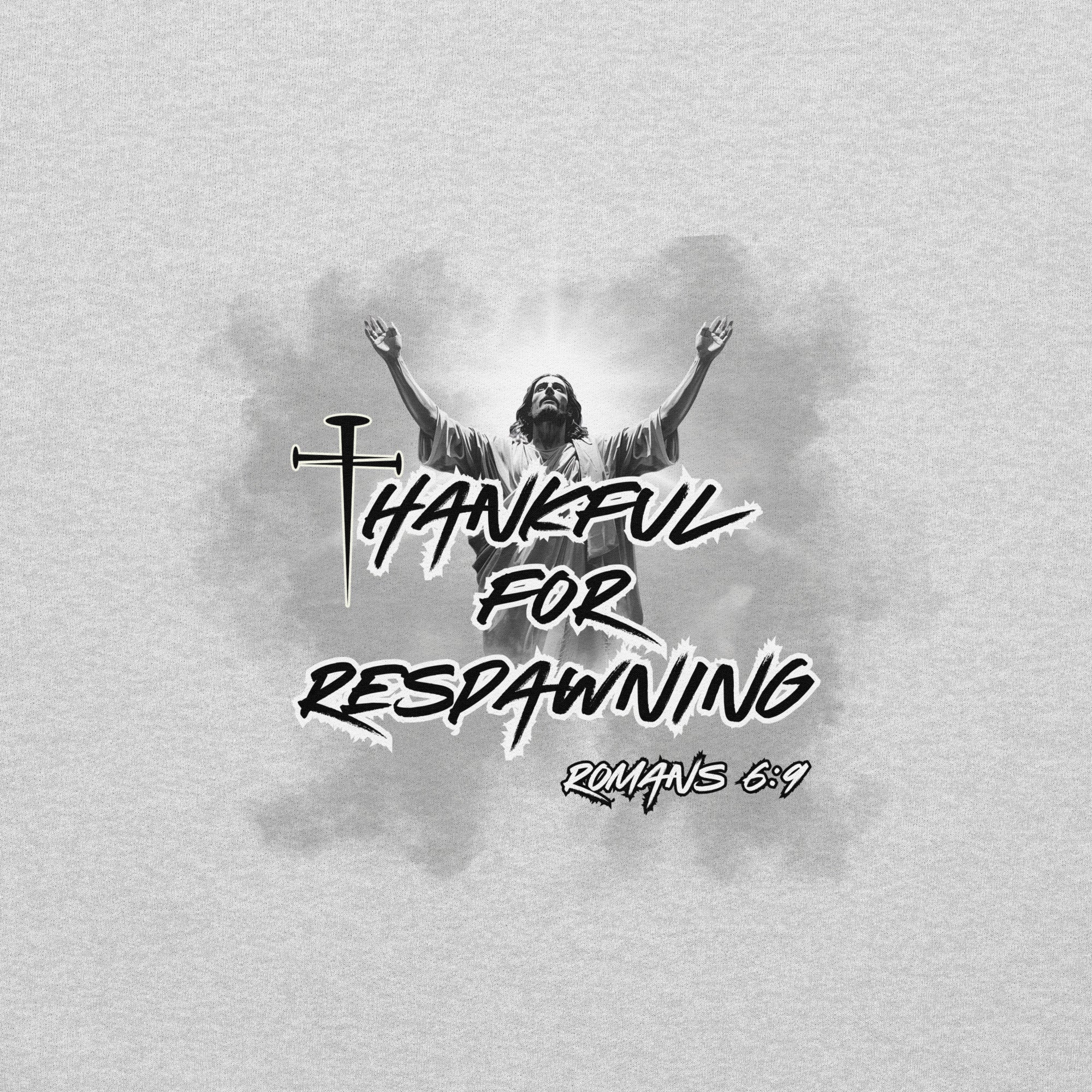 Close-up view of the ash gray men’s Christian hoodie highlighting the full design text “Thankful for Respawning” and “Romans 6:9,” the three-nail “t” in Thankful, and Jesus looking to Heaven with His arms raised with light and clouds behind Him.