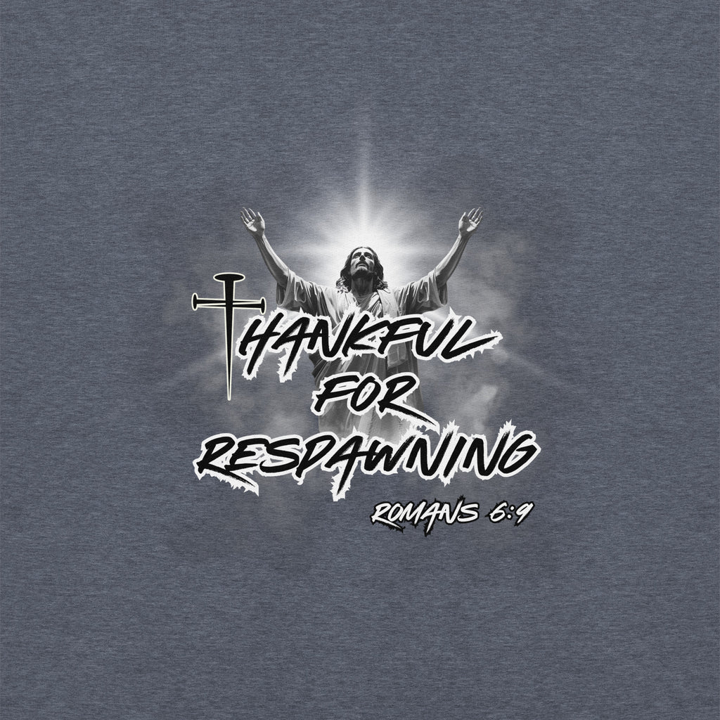 Close-up of the heather sport dark navy men’s Christian hoodie featuring the full design text “Thankful for Respawning” and “Romans 6:9,” the “t” made from three nails, and Jesus looking to Heaven with His arms raised with light rays and clouds behind Him.