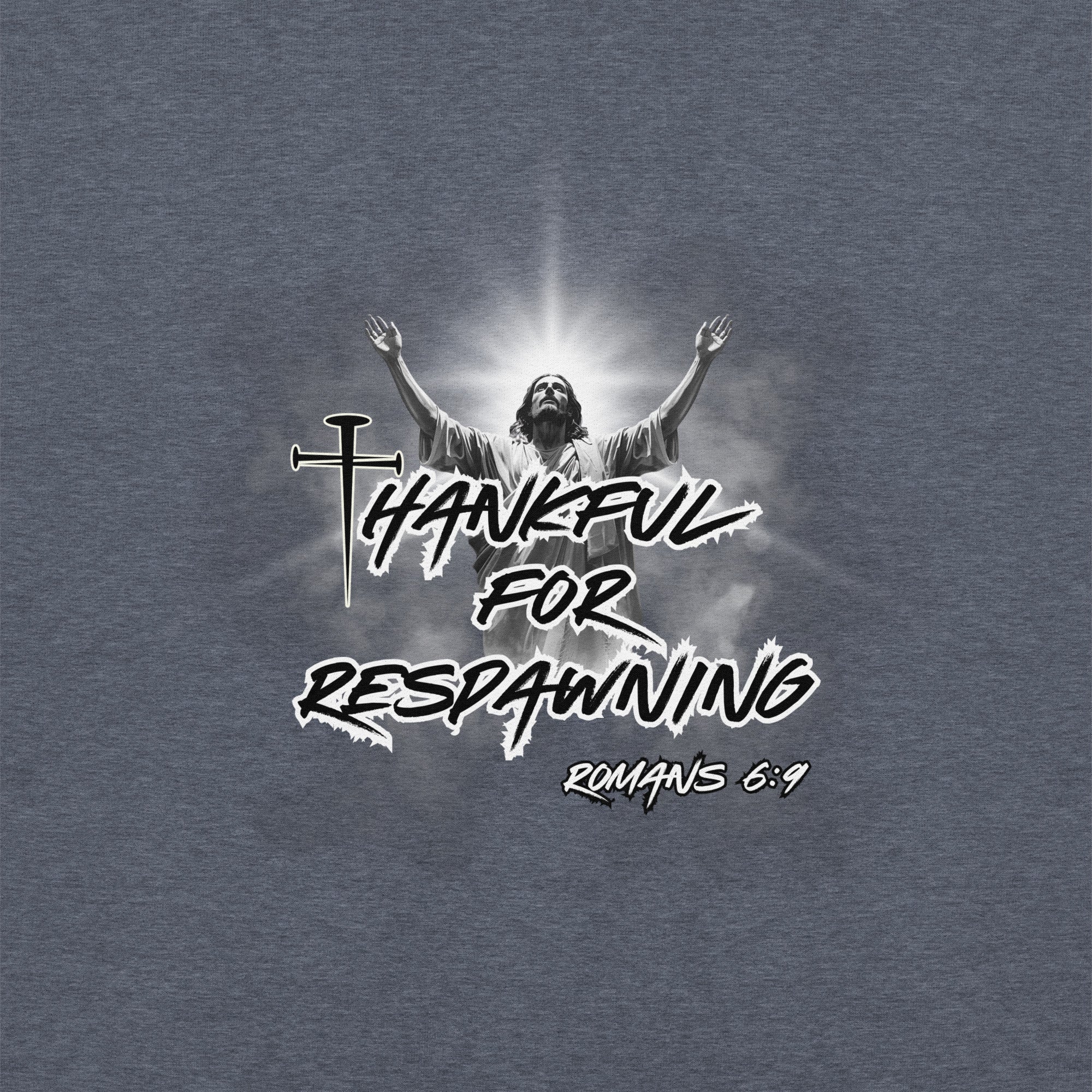 Close-up of the heather sport dark navy men’s Christian hoodie featuring the full design text “Thankful for Respawning” and “Romans 6:9,” the “t” made from three nails, and Jesus looking to Heaven with His arms raised with light rays and clouds behind Him.