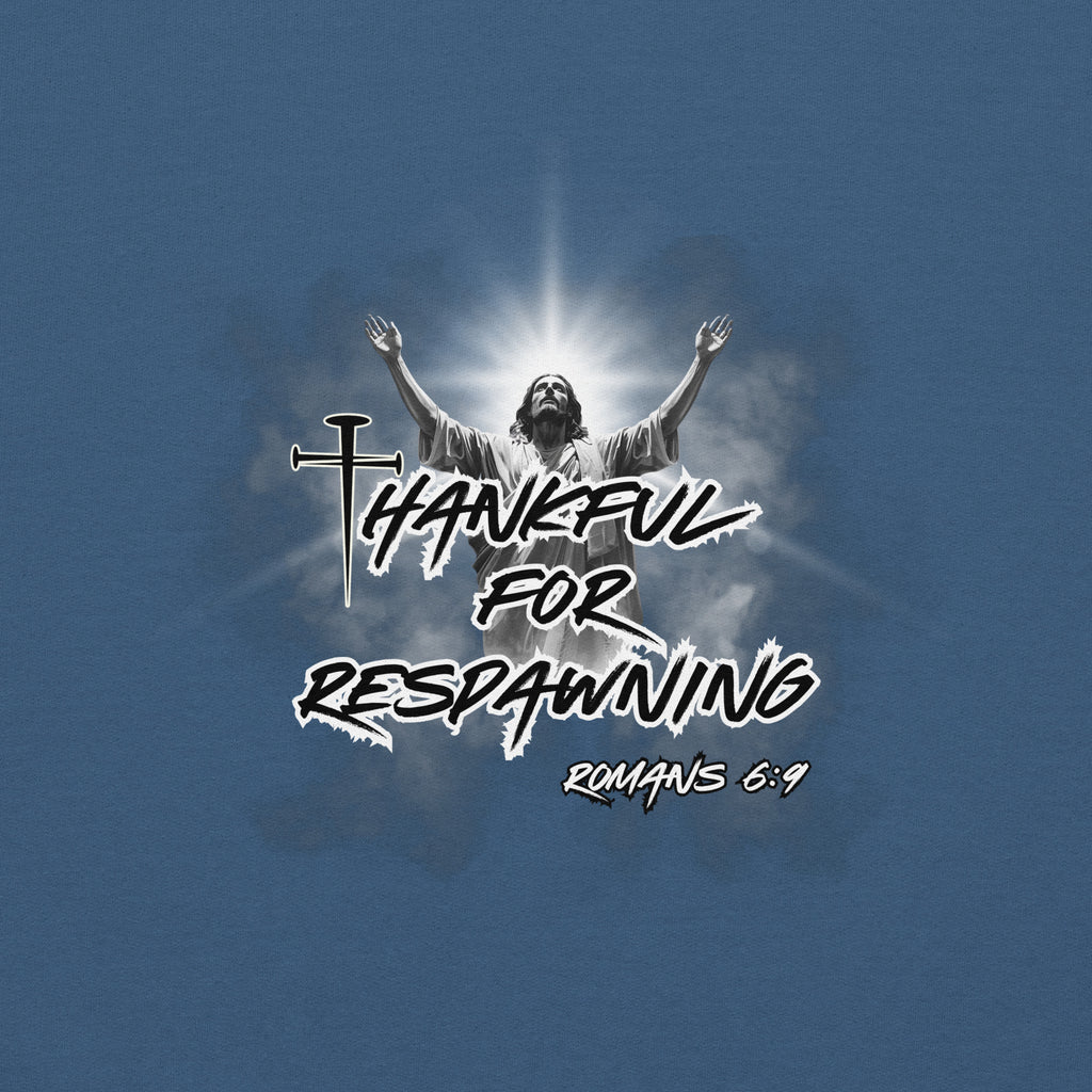 Close-up detail of the indigo blue men’s Christian hoodie showing the full design text “Thankful for Respawning” and “Romans 6:9,” the “t” in Thankful created with three nails, and Jesus looking to Heaven with His arms raised with light and clouds behind Him.
