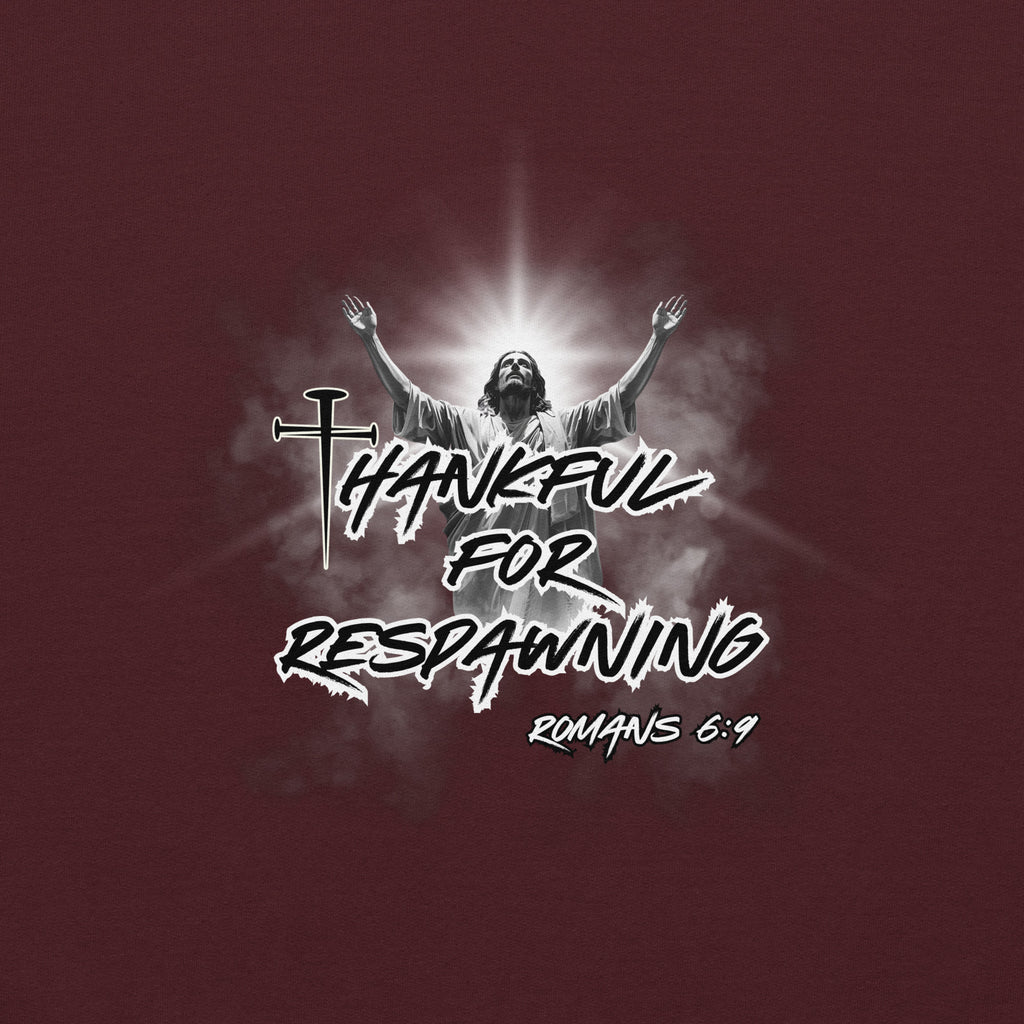 Close-up detail of the maroon men’s Christian hoodie showing the full design text “Thankful for Respawning” and “Romans 6:9,” the three-nail “t” in Thankful, and the image of Jesus looking to Heaven with His arms raised with light and clouds behind Him.