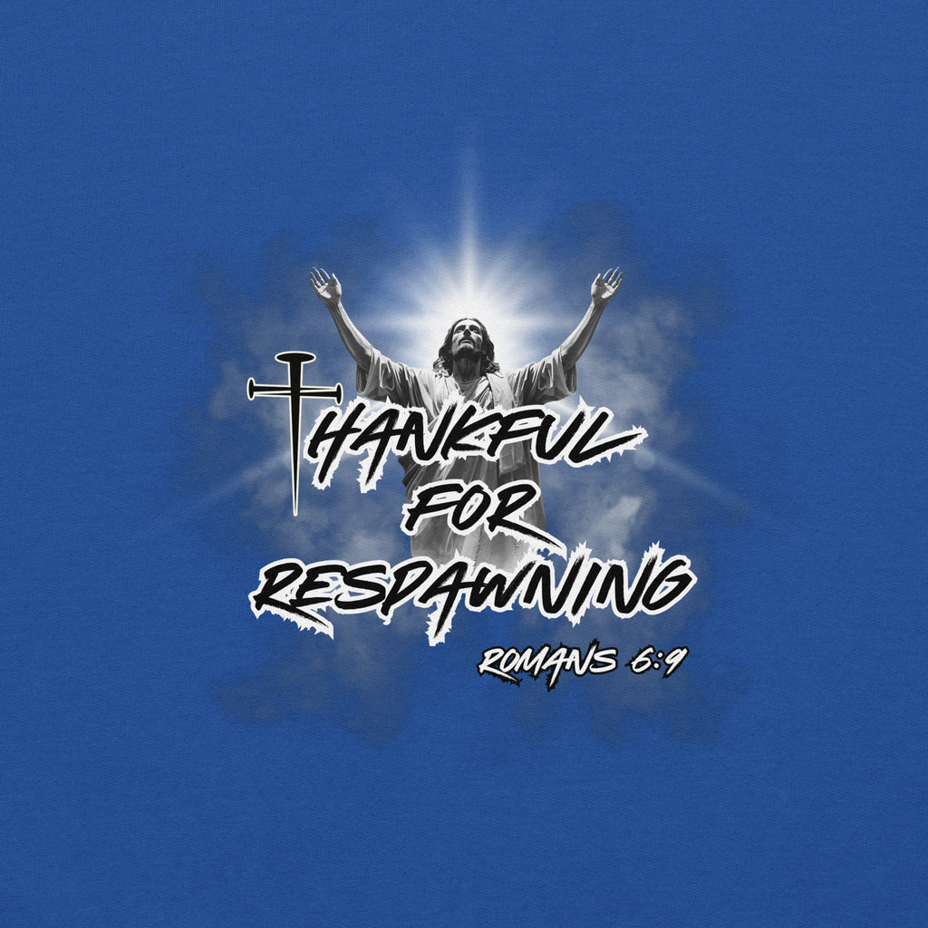 Close-up view of the royal blue men’s Christian hoodie highlighting the full design text “Thankful for Respawning” and “Romans 6:9,” the three-nail “t” in Thankful, and Jesus looking to Heaven with His arms raised with light rays and clouds behind Him.