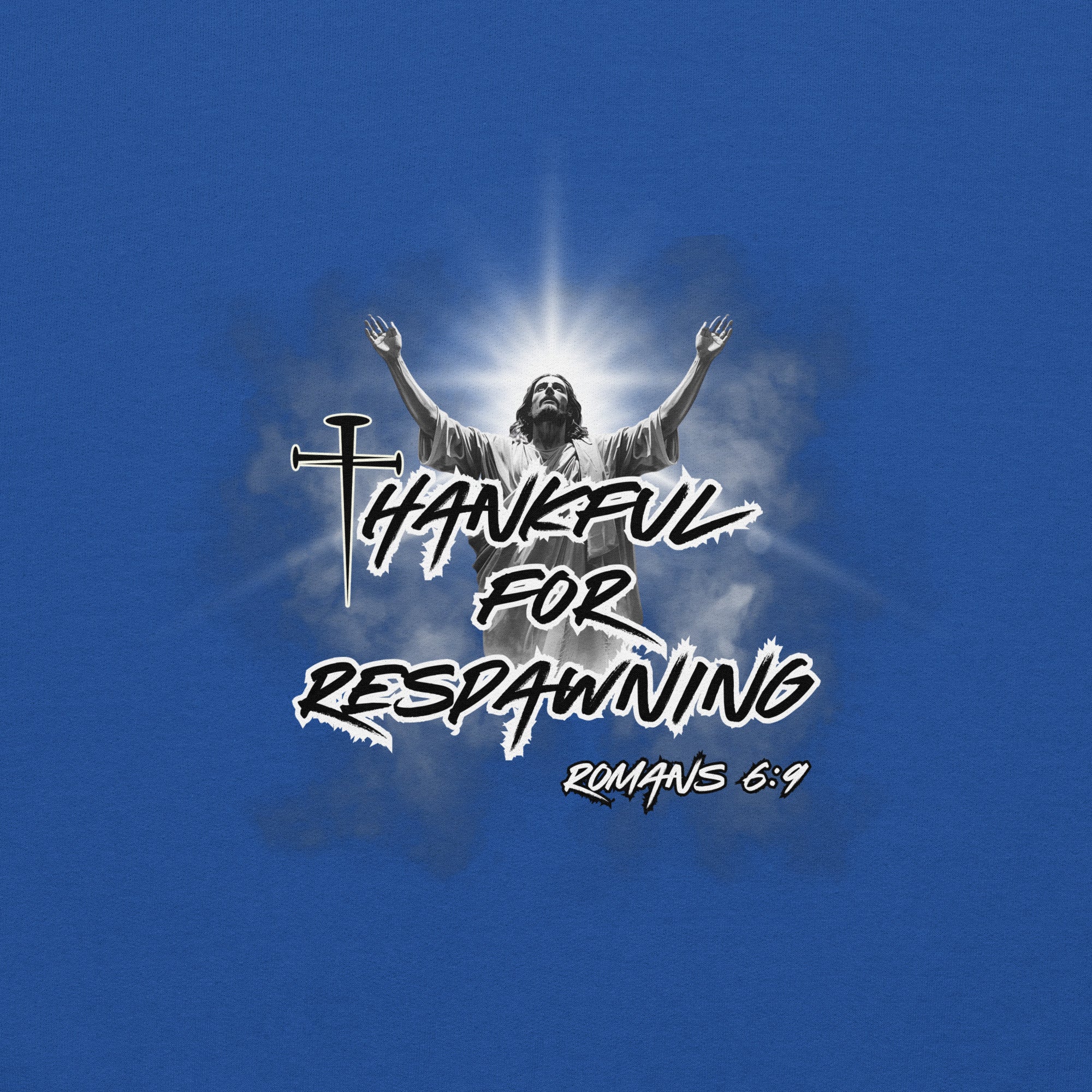 Close-up view of the royal blue men’s Christian hoodie highlighting the full design text “Thankful for Respawning” and “Romans 6:9,” the three-nail “t” in Thankful, and Jesus looking to Heaven with His arms raised with light rays and clouds behind Him.