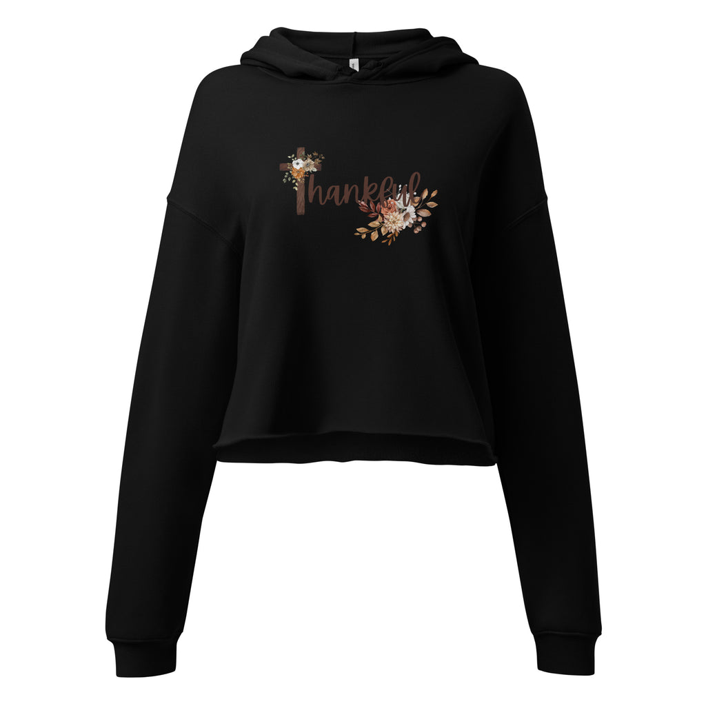 Flat lay front view of a women’s cropped Christian hoodie in black featuring the word “Thankful” in a brown script font, the “T” designed as a wooden cross, and soft fall floral accents.