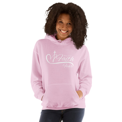 Woman model smiling while wearing a light pink Christian hoodie featuring the word “Faith” above the word “Fear,” separated by an elegant white heart and cross design, referencing Isaiah 41:10
