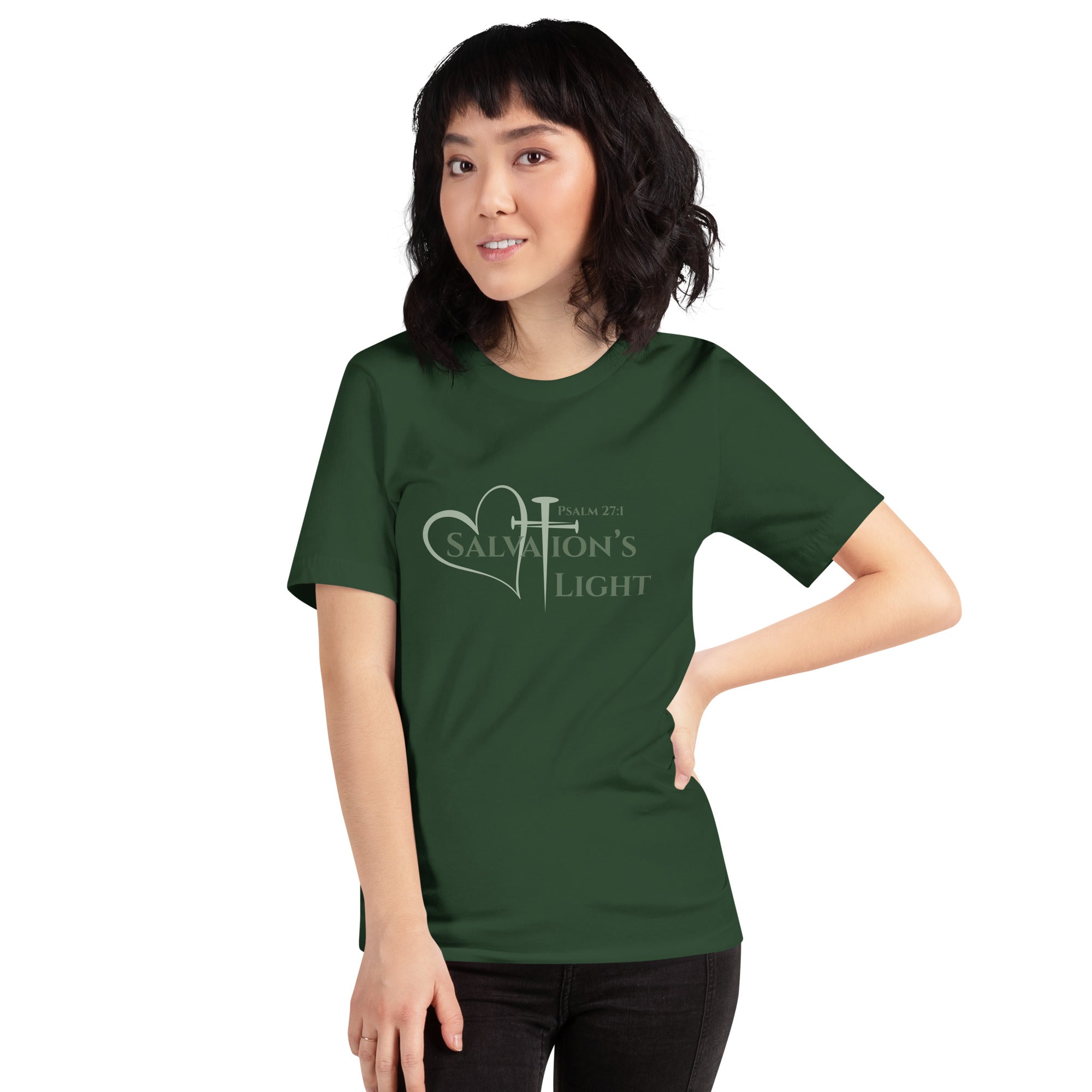 Female model wearing a forest green short sleeve t-shirt from the Salvation’s Light Signature Collection, featuring Psalm 27:1 and the word “Salvation’s Light,” with the T designed as a sage green three-nail cross and accompanied by a sage green heart
